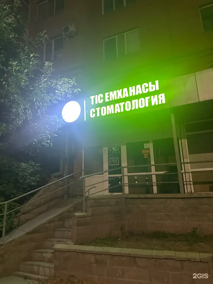 Вход в клинику Ай Дент ночью, зелёная вывеска «Стоматология»